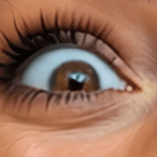 Close-up of a wide open brown eye with visible eyelashes and detailed skin texture around it.
