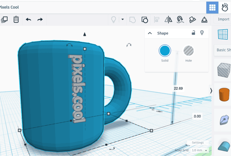 A 3D modeling software interface showing a blue mug with the text "pixels.cool" on its side.
