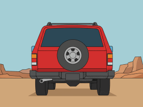 A red SUV is parked on a dirt road in a desert landscape with rock formations in the background.