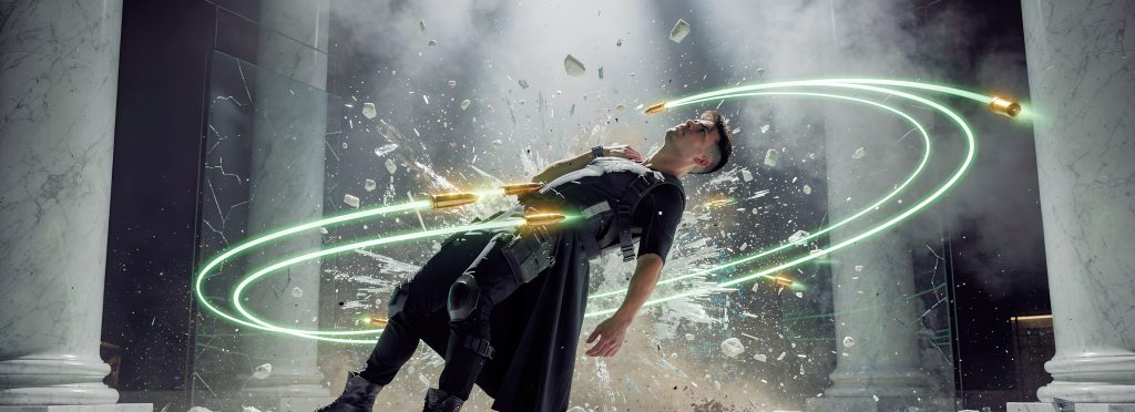 Person leaning backward as bullets and glowing rings encircle them; glass shatters and debris flies amid marble columns.