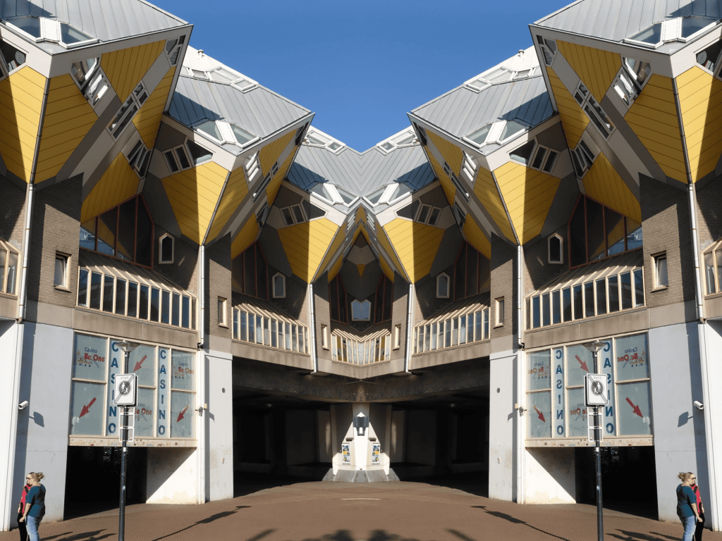 Symmetrical view of modern yellow and gray cube-shaped buildings with blue sky above.